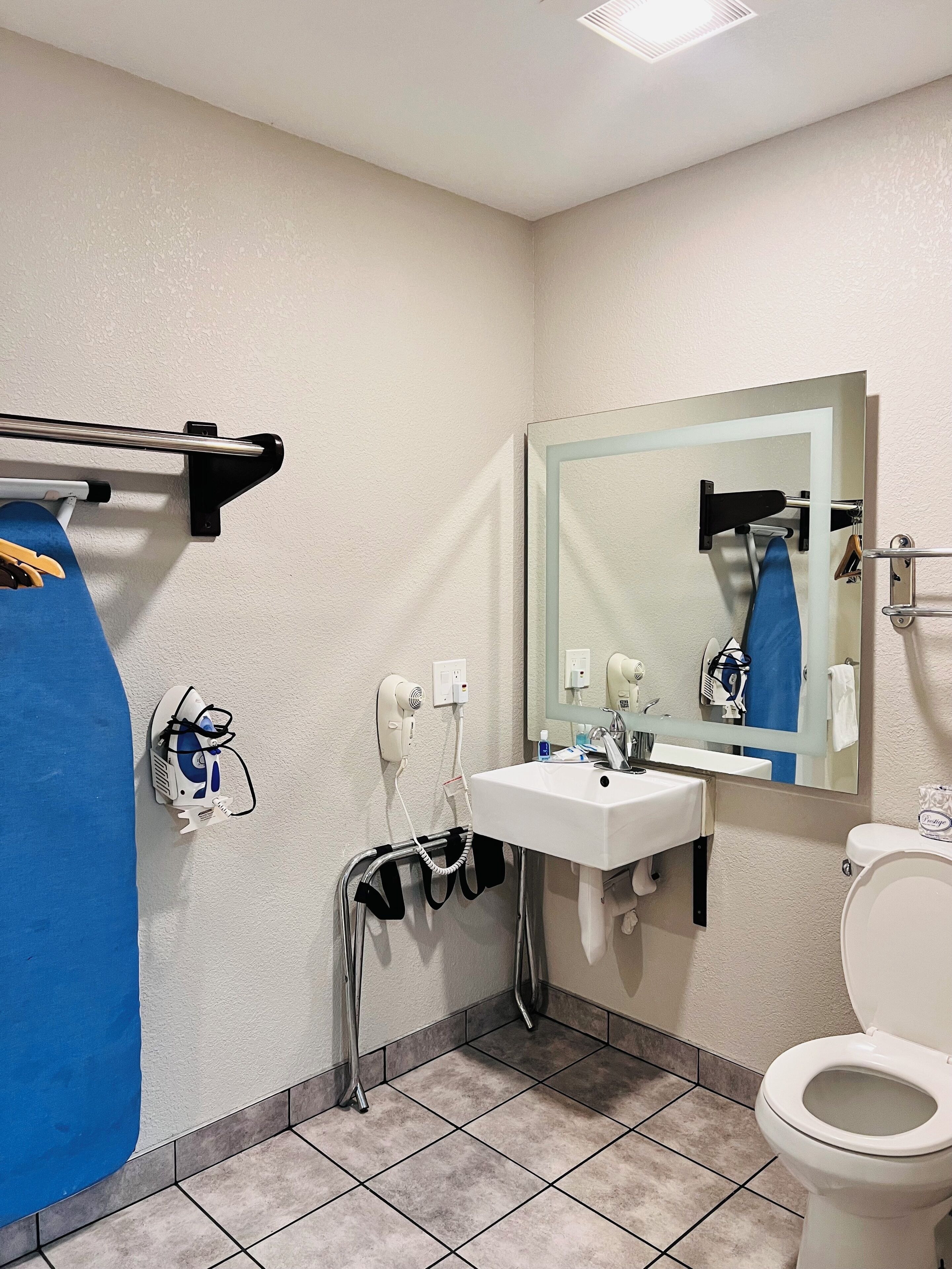 Un baño con un lavamanos blanco, un espejo, un inodoro y un secador de pelo montado en la pared.