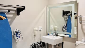 A bathroom with a white sink, a mirror, a toilet, and a hairdryer mounted on the wall.
