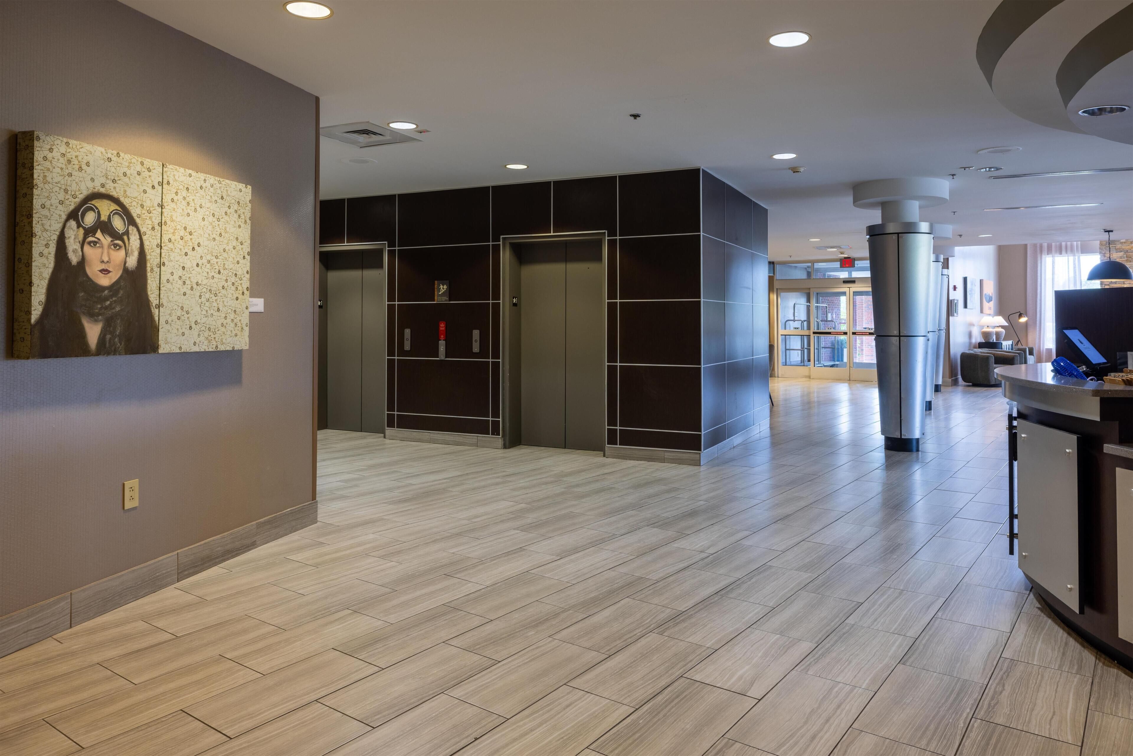 Un hall de hotel de diseño moderno, con piso de madera, un mostrador de recepción y un cuadro grande en la pared.