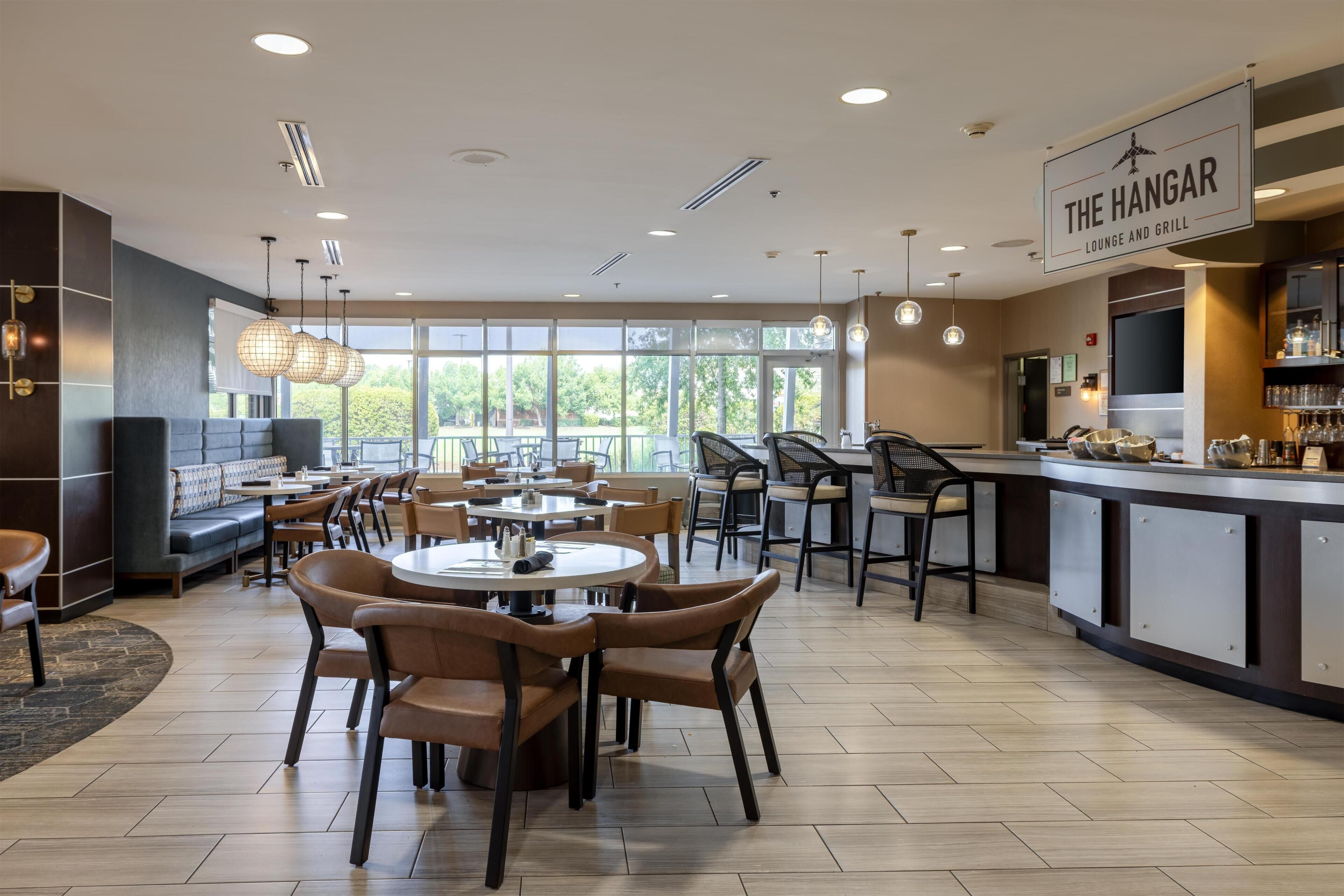 A restaurant interior with round tables, chairs, and a bar area.