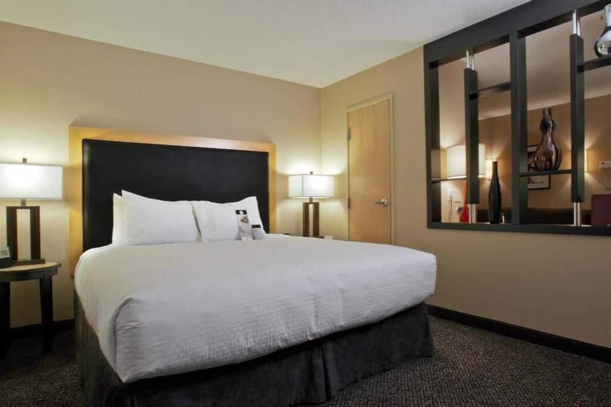 A hotel room with a large bed, two bedside tables, a mirror, and a door.