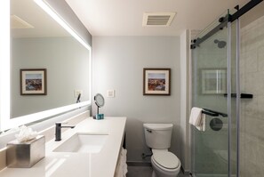 Une salle de bain moderne avec un grand miroir, un lavabo, des toilettes et une douche à parois de verre.