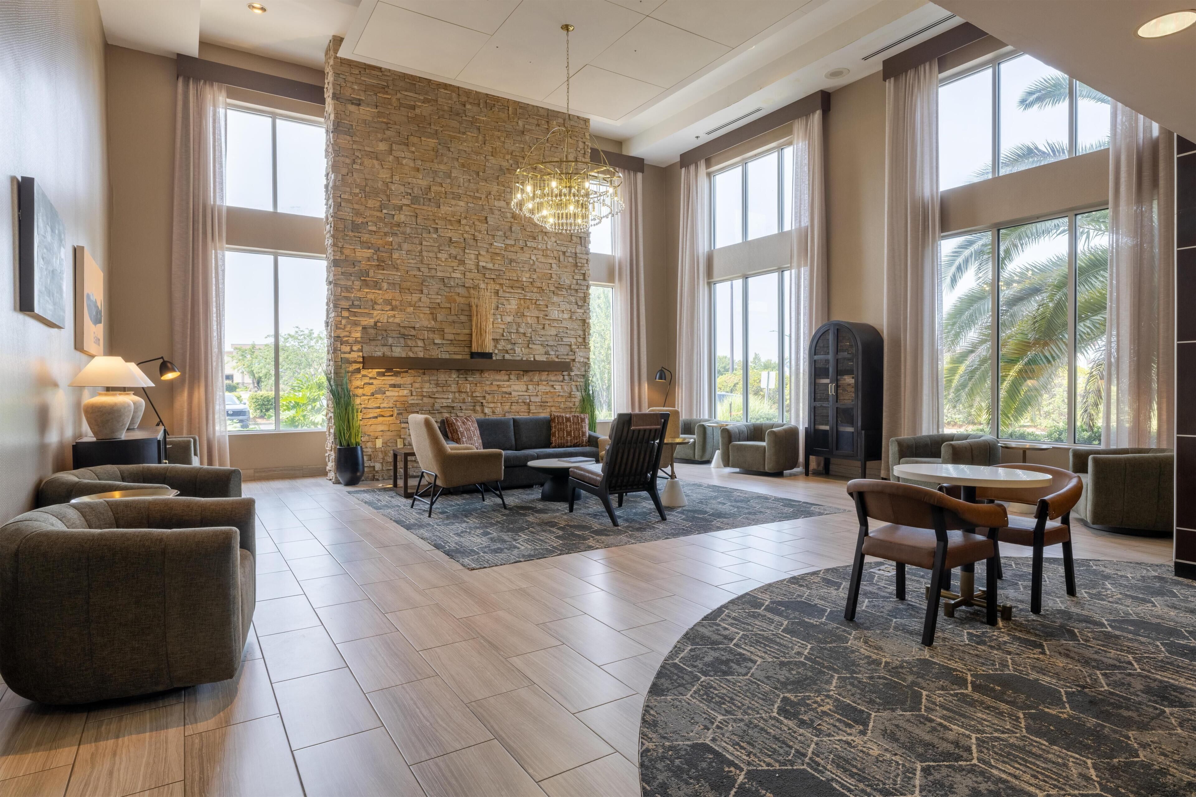 A spacious living area with a stone accent wall, modern furniture, and large windows.