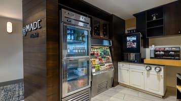 Una kitchenette con un refrigerador empotrado lleno de bebidas, una cafetera y un microondas.
