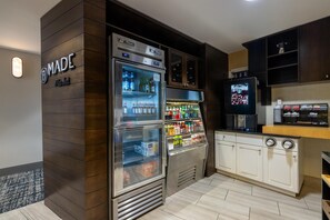 A kitchenette with a built-in refrigerator stocked with beverages, a coffee machine, and a microwave.