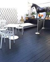 Zona relax esterna moderna con sedie e tavoli bianchi, una statua decorativa a forma di cavallo e piante in vaso.