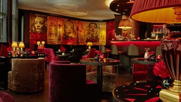 Uma área de lounge com iluminação suave, poltronas confortáveis, um bar e um grande mural na parede.