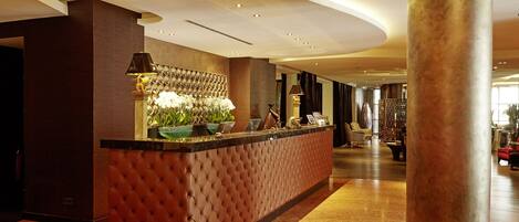 A reception area with a tufted brown counter, a large metallic column, and a well-lit interior.