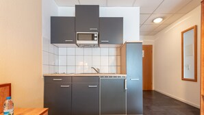 A modern kitchen with dark cabinets, a microwave, and a dishwasher. - Boardinghouse Burgpark (Huerth)