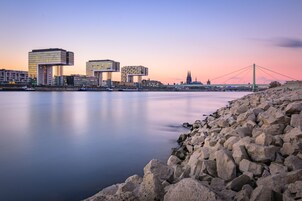 Un paisaje urbano frente al agua, con edificios modernos, un puente y una catedral histórica.