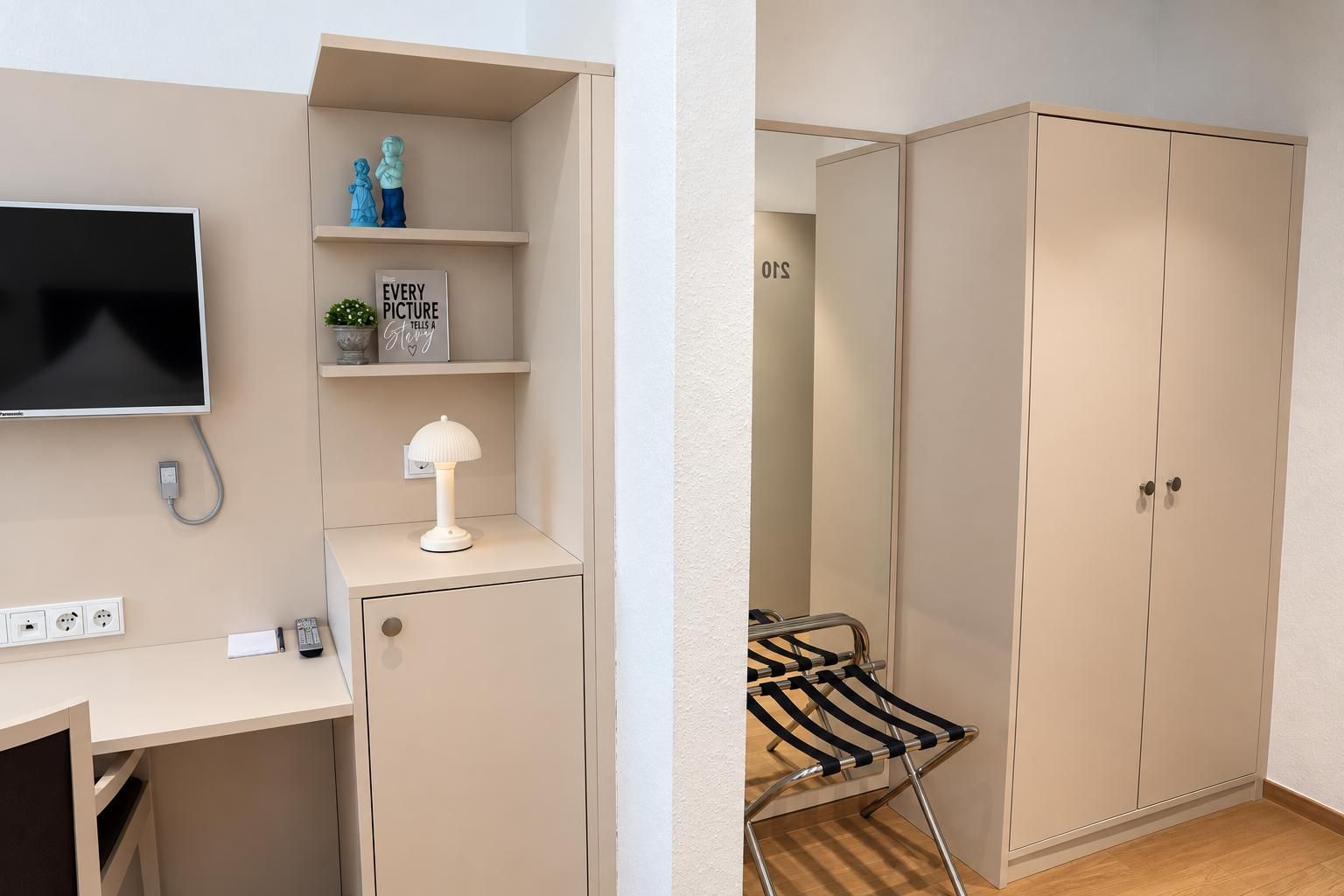 A room with a bed, bedside table, lamp, TV, and wardrobe.