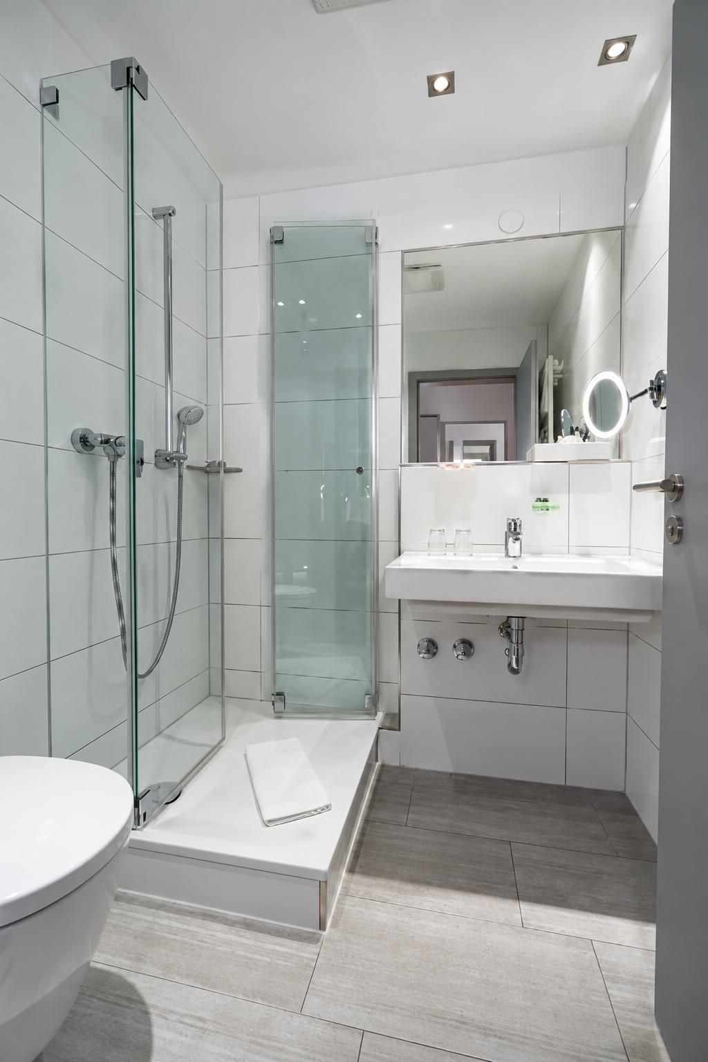 Une salle de bain moderne avec une douche à parois de verre, un lavabo blanc avec un miroir et des toilettes.
