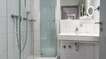 Ein modernes Badezimmer mit Duschkabine aus Glas, Waschbecken mit Spiegel und Toilette.