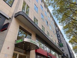 Un hotel con una facciata moderna, numerose finestre e un ingresso ben visibile con un tendone curvo.