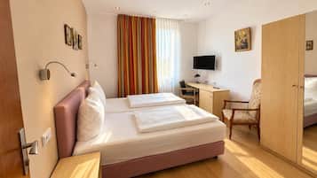 Une chambre d’hôtel équipée d’un lit, d’un bureau, d’une chaise, d’une télévision et d’une armoire.