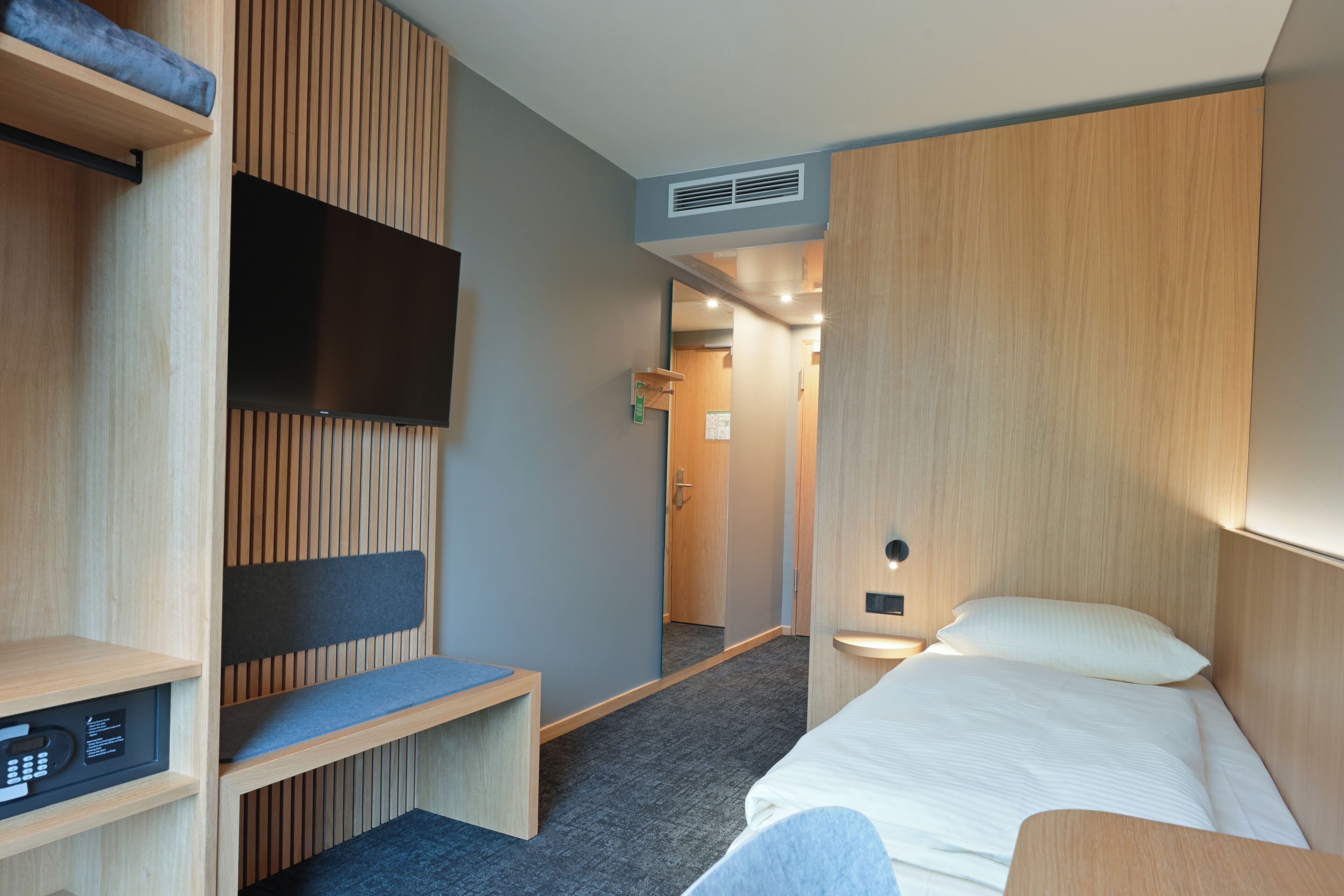 Habitación de hotel con cama, escritorio, televisión y zona de ducha.