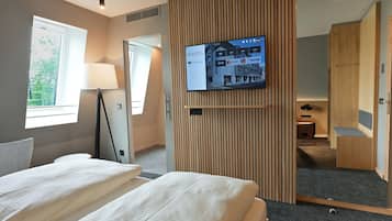 Een hotelkamer met een bed, een aan de muur bevestigde televisie, een lamp en een raam.