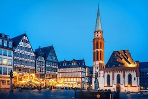 Una piazza storica con edifici tradizionali a graticcio e un'imponente torre campanaria.