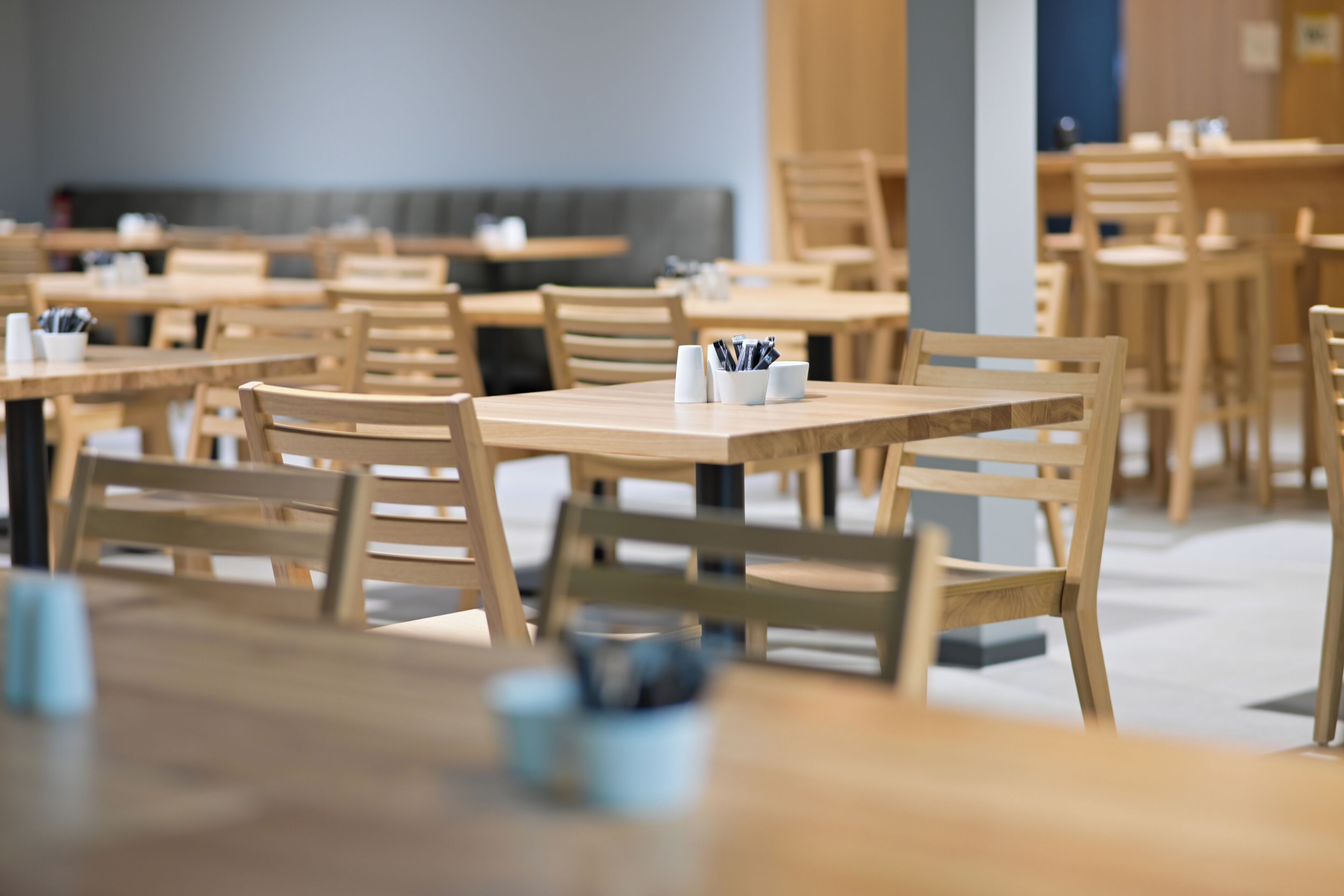 Ein Restaurant mit Holztischen und -stühlen, einige mit Gewürzen.