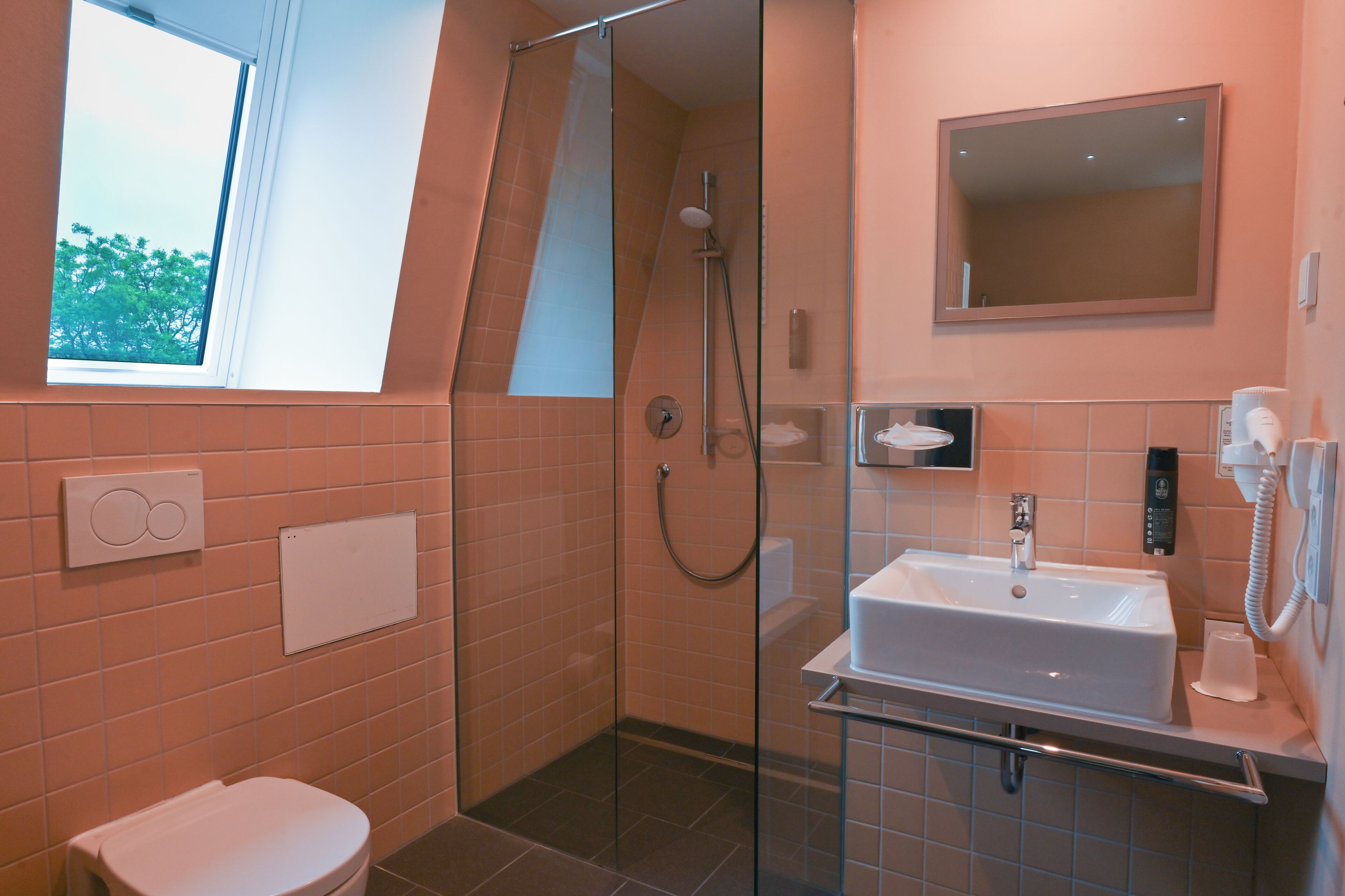 Un baño moderno con ducha envuelta en vidrio, un lavabo con espejo y un inodoro.
