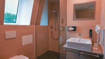Un baño moderno con ducha envuelta en vidrio, un lavabo con espejo y un inodoro.