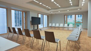 A conference room with a long table, chairs, a TV, and large windows.