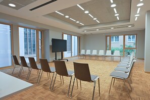 Una sala conferenze con un lungo tavolo, sedie, un televisore e ampie finestre.