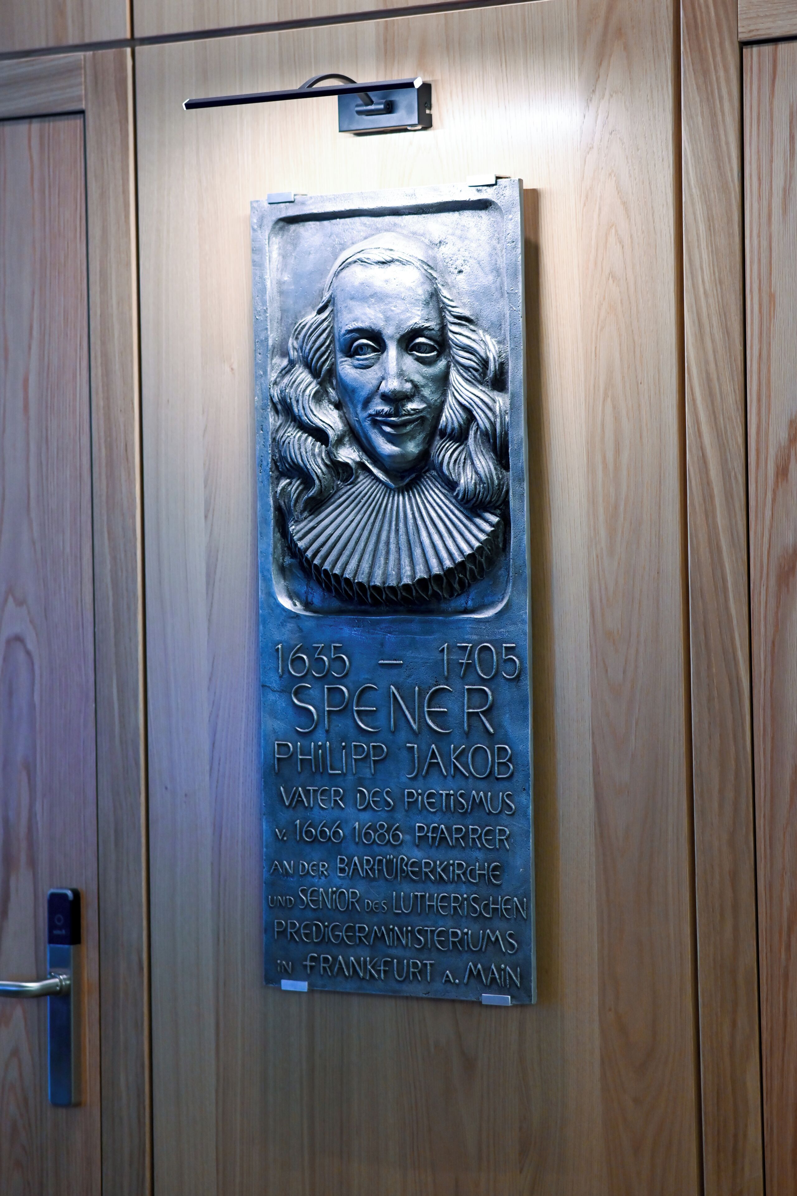A plaque with a portrait and text on a wooden door.
