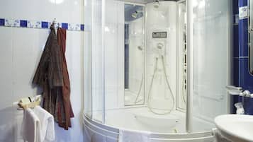 A modern bathroom with a glass-enclosed shower, a white sink, and a patterned rug on the floor.