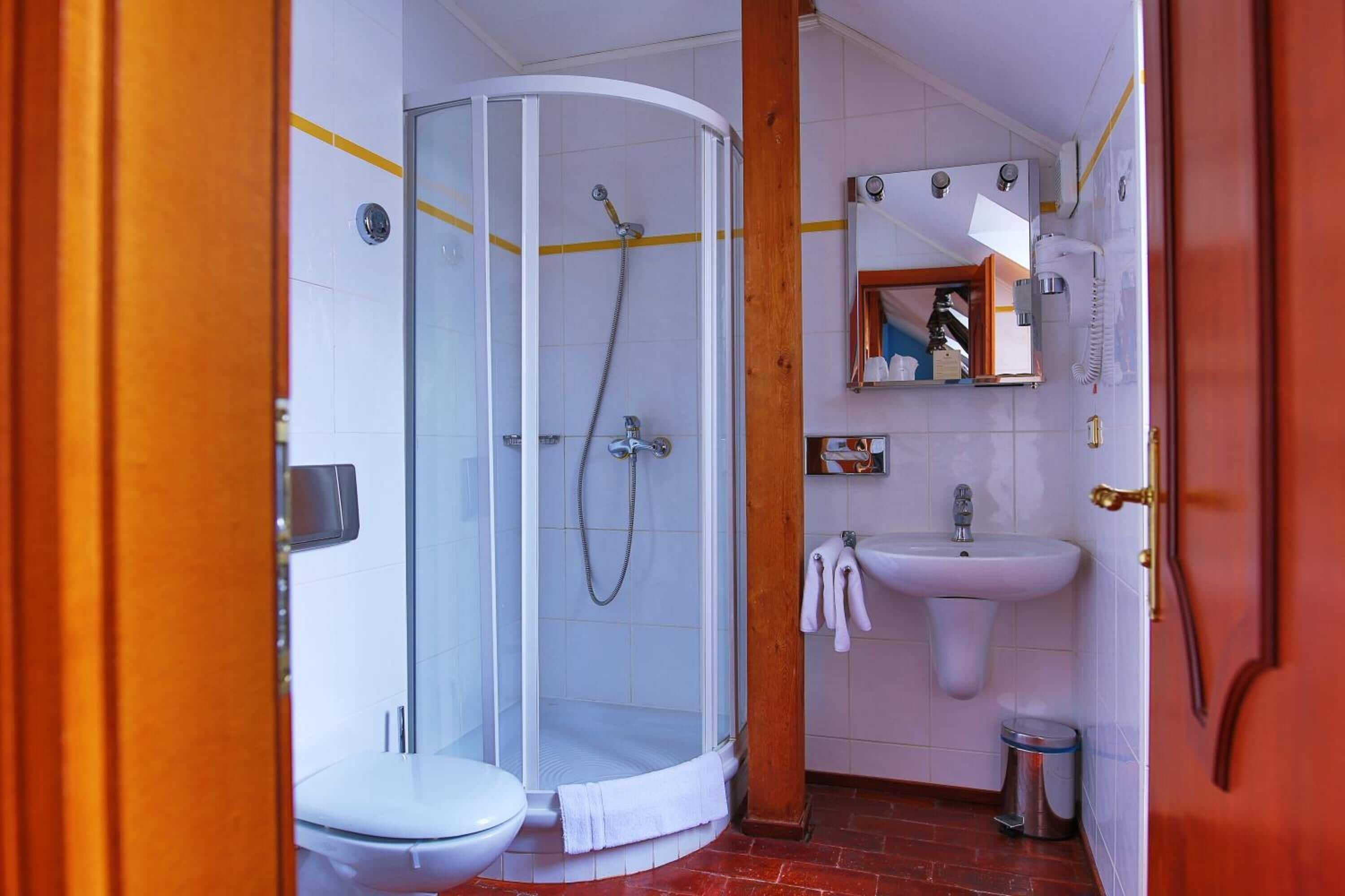 Un baño con ducha de vidrio, un lavamanos blanco y un inodoro.