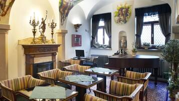 Un comedor espacioso con techos altos, candelabros ornamentales y una chimenea.