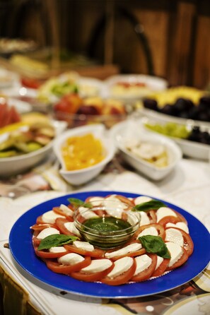 A table with various dishes, including a plate of tomato and mozzarella salad with a basil garnish.