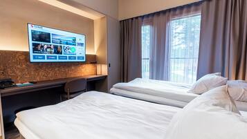 Une chambre d’hôtel avec deux lits, un bureau avec un ordinateur et un téléviseur affichant un site web.