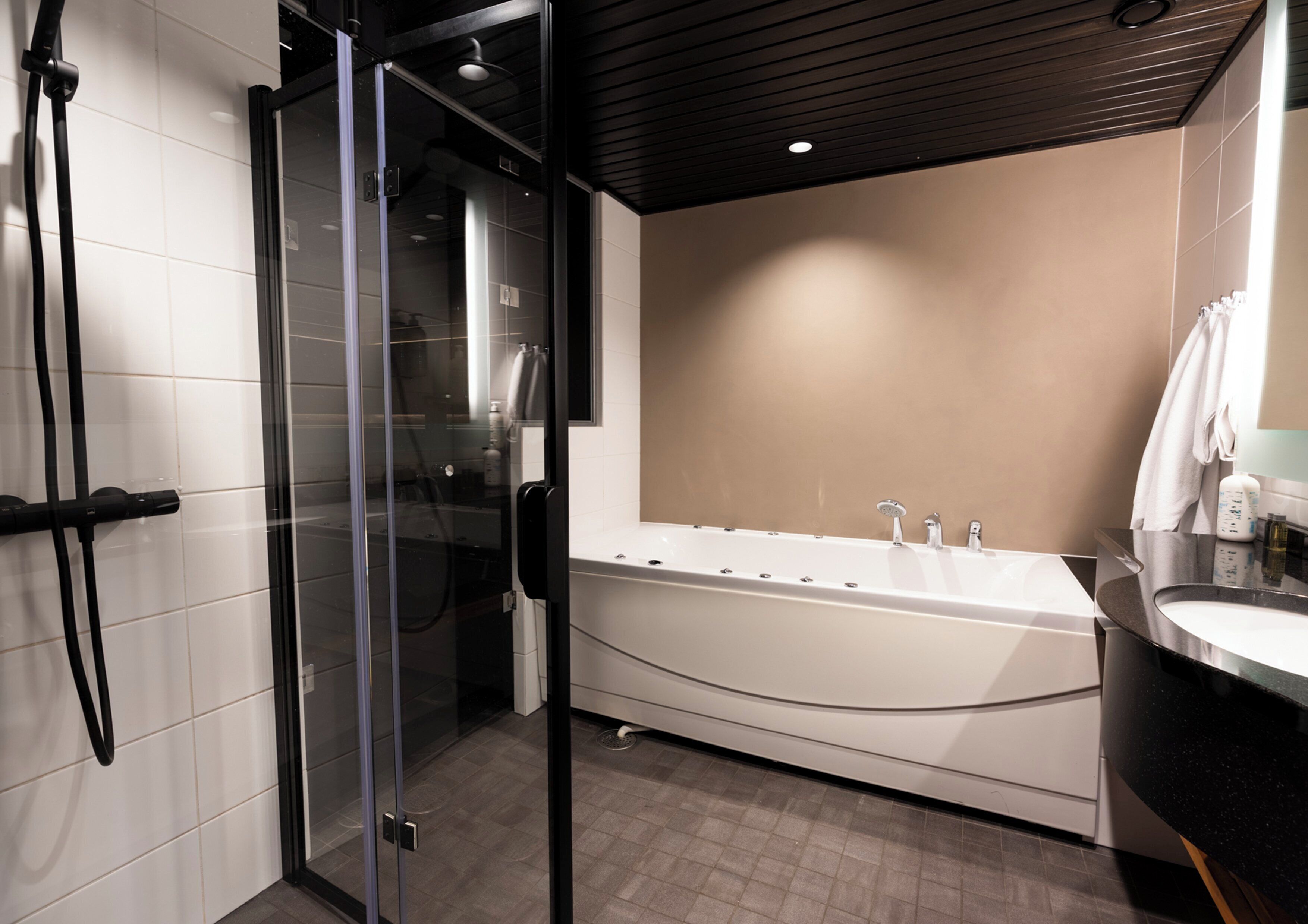 A modern bathroom with a glass-enclosed shower, a freestanding bathtub, and a vanity with a mirror.