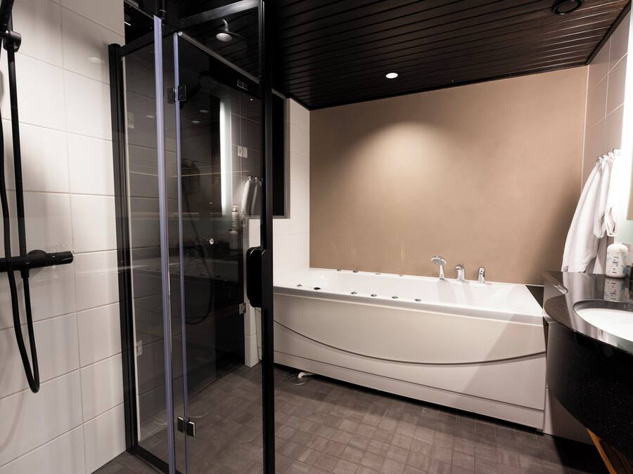 Een moderne badkamer met een douchecabine van glas, een vrijstaand bad en een wastafel met spiegel.