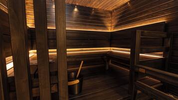 A sauna with wooden benches and a metal bucket.