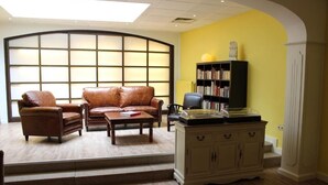 Uma sala de estar com sofá, poltrona, mesa de centro e estante.