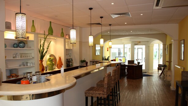 Um hall de hotel moderno com um balcão de recepção curvo, banquetas de bar e luminárias pendentes.