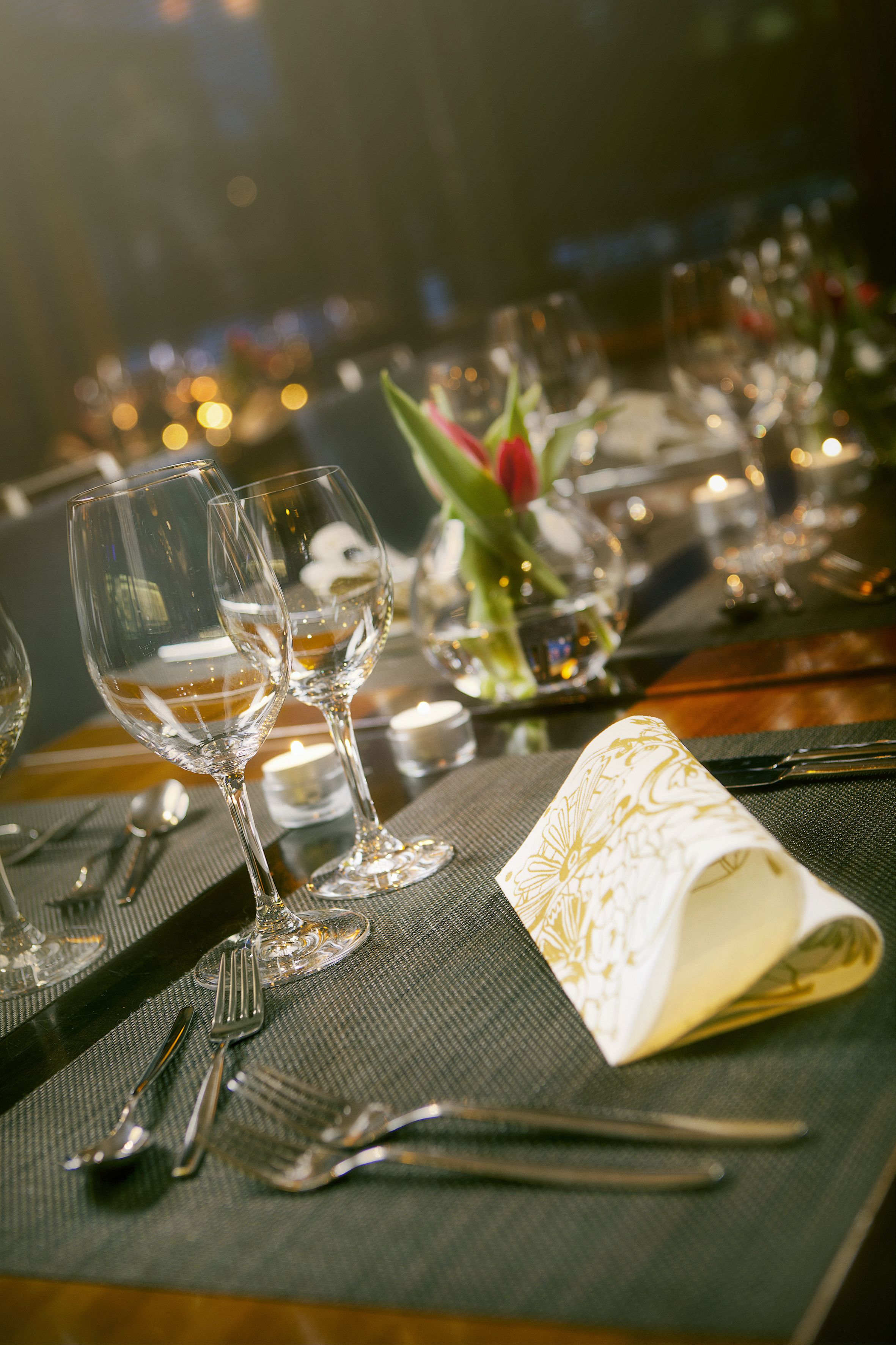 Une table dressée avec des verres à vin, des couverts et une serviette pliée.