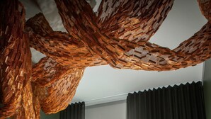 A hotel room with a bed, a desk with a laptop, a chair, a window with curtains, and a unique woven ceiling light fixture. - Hotel Lasaretti (Oulu)