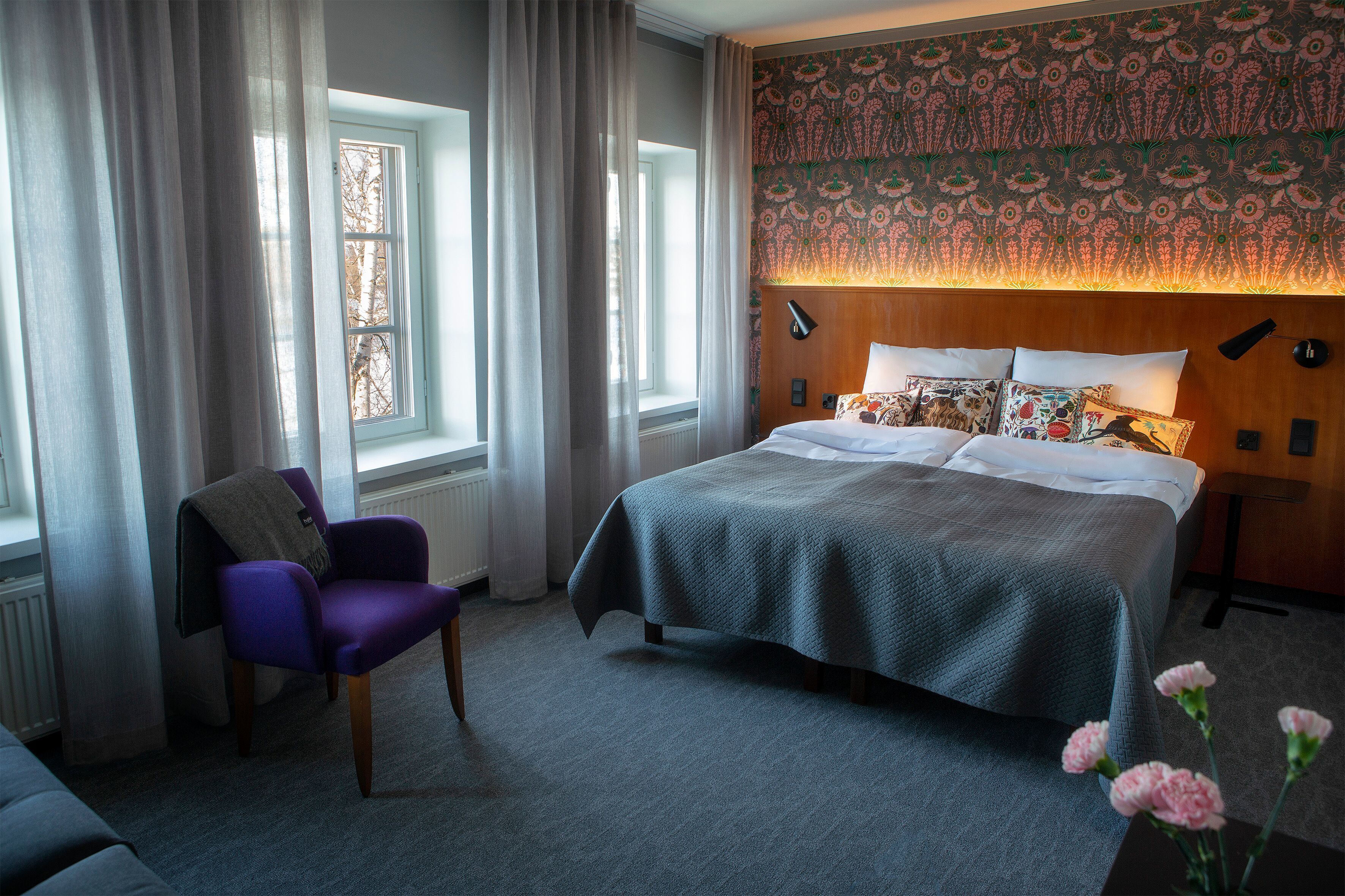Un dormitorio con una cama grande, una silla y una ventana con cortinas.
