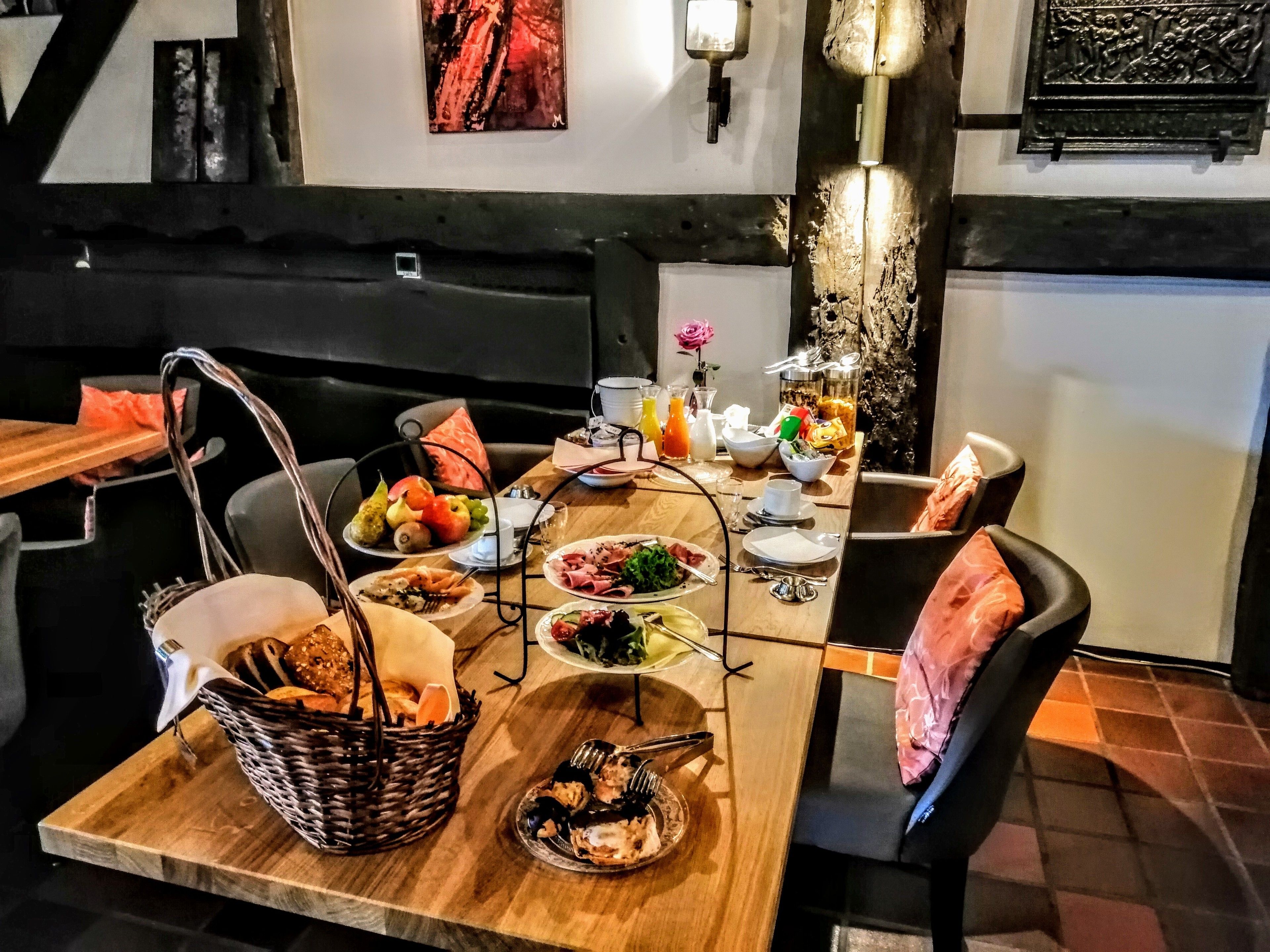 En restaurang med ett matbord i trä, dukat för en måltid, omgivet av stolar.