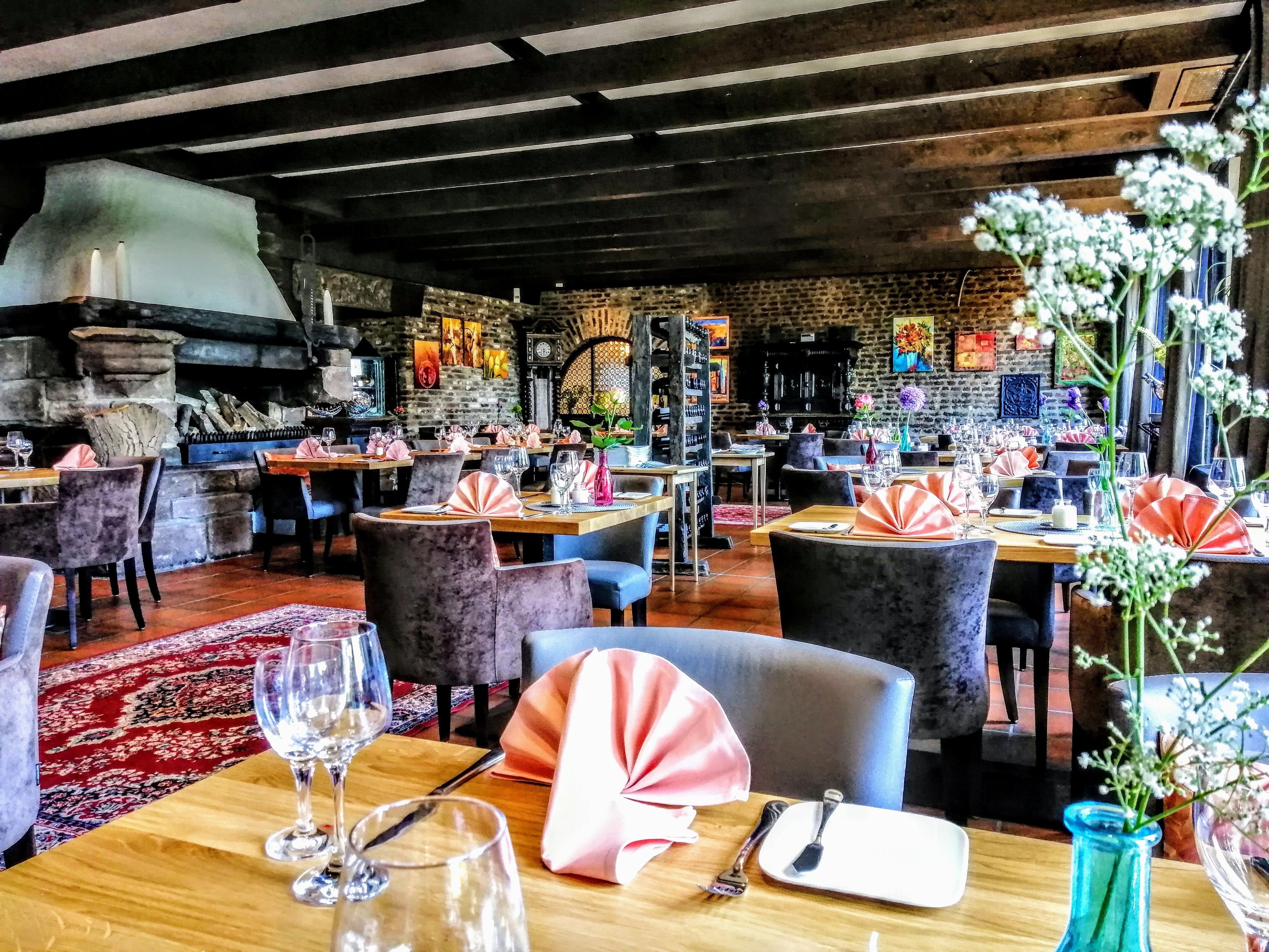 Ein Restaurant mit Holztischen, Stühlen und einer Steinsäule im Hintergrund.