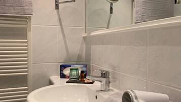 A bathroom with a white sink, a mirror, a towel rack, and a hairdryer.
