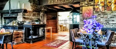 Un intérieur rustique avec des murs en briques apparentes, une cheminée en pierre et un coin repas doté de meubles modernes.