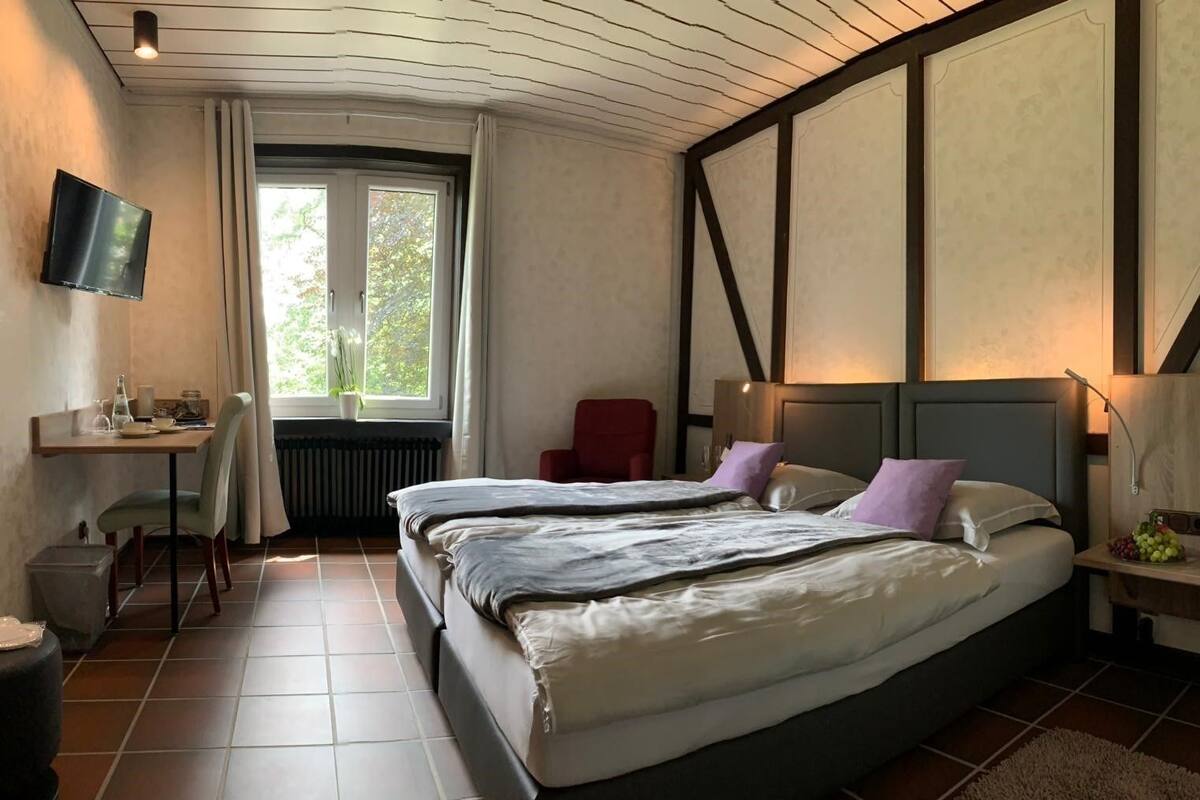 A bedroom with a large bed, a desk, a chair, and a TV.