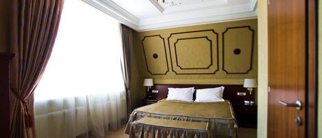 A hotel room with a large bed, a chandelier, and a view of the outdoors.