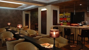 A bar area with a long counter, multiple bar stools, and a selection of bottles on shelves. - Aurora Premier Hotel (Kharkiv)