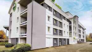 Un moderno edificio hotelero con varios pisos, balcones y un llamativo letrero de B&B Hotels.