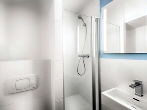 A modern bathroom with a glass-enclosed shower, a white sink, and a mirror above the sink. - B&B Hotel Köln-Frechen (Frechen)